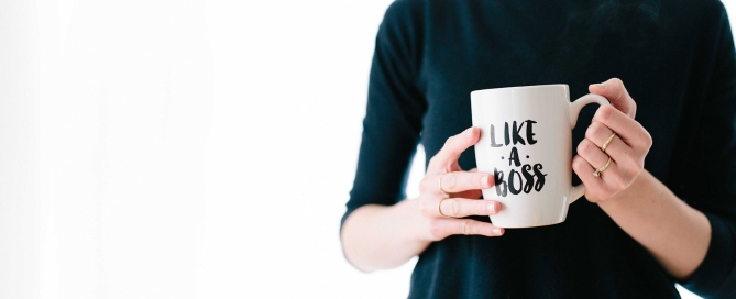 Symbolizing leadership confidence, a tech leader holds a "Like a Boss" mug (woman, torso)