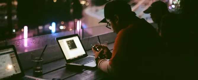 Nearshore App Development for Blockchain: person working late, facing laptop inside dark room
