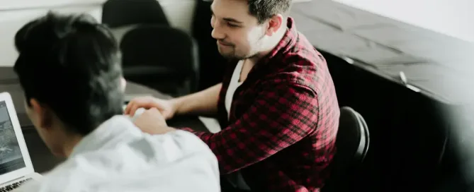 Nearshore App Development for FinTech - Man sitting at a desk shaking hands with another man sitting nearby