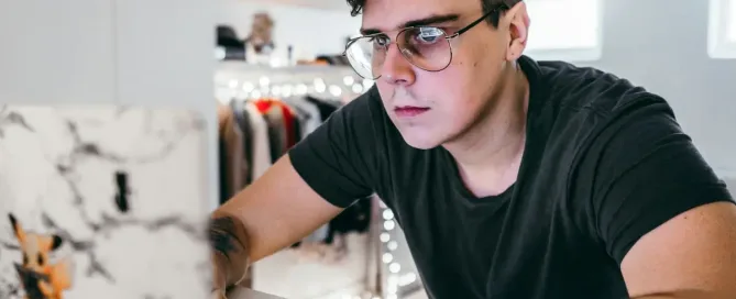 Nearshore Software Development Providers: tattooed man in black tshirt leans toward computer with serious face