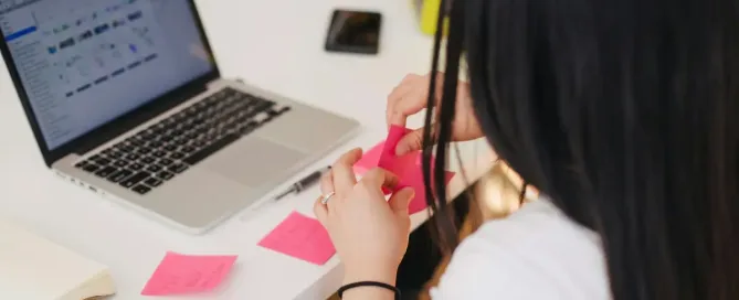 No-Code Development: woman sitting beside table, writing on sticky notes