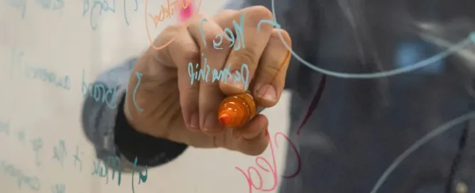 Microservices Architecture: person holding orange marker, writing on glass