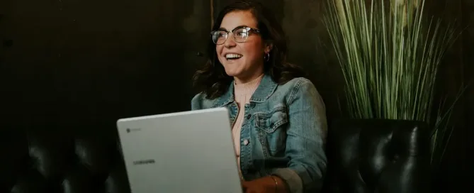 Antibias: female leader laughs while sitting with a silver notebook on lap