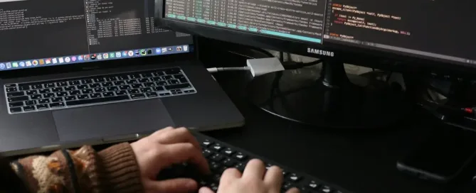 Person coding at a desk with laptop and monitor. Exploring functional programming concepts for cleaner code.