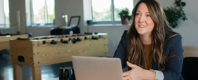 Confident businesswoman reviewing data on laptop at modern office desk. Seeking top talent? Optimize compensation strategies.