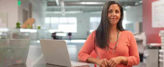 Job evaluation: woman in orange long sleeve shirt sitting beside table with macbook pro