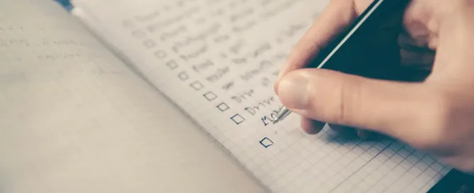 Handwriting a checklist in a notebook, symbolizing the creation of a personal learning and development plan.