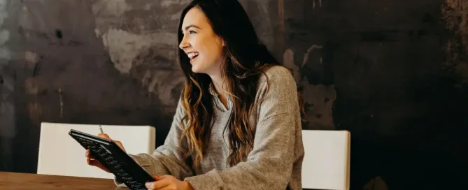 Tech recruiter holding a notebook smiles at candidate, symbolizing a successful talent acquisition pipeline