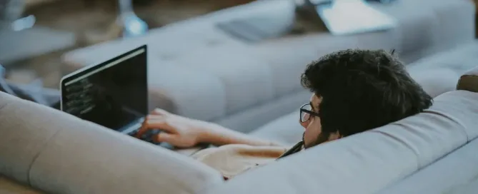 developer burnout: man lying on couch while browsing the internet