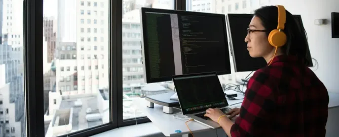 developer salary: woman using MacBook Pro to code looks out the window