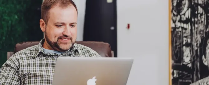 developer guide: man smiling and using MacBook on his lap