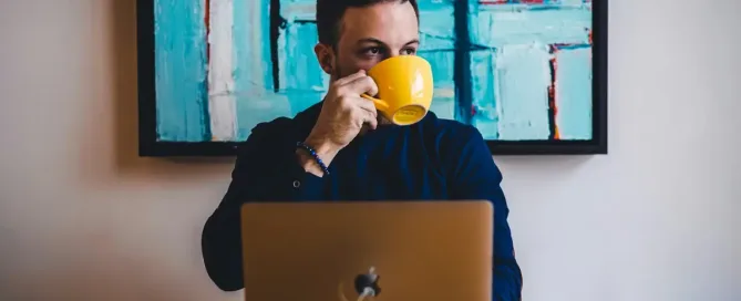 Hire a coder: man drinking coffee in front of the laptop computer