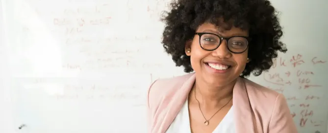 market research tools: female marketer smiles in front of whiteboard