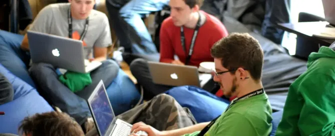 tech talent development: man sitting on blue bean bag using laptop during a tech event.