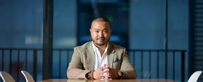 financially sustainable business: young asian american business man sits at the end of a meeting room