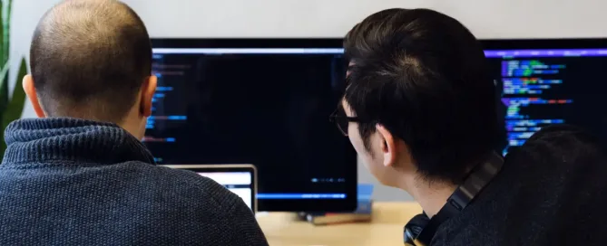 software interrupts: Computer programmer takes a look at colleague's laptop to review the programming code on the screen.