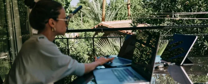 trabalho remoto. A girl working on the table on the terrace. Many laptops and other staff. Side view