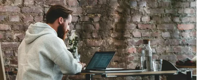 Assess Candidate Tech Skills: man in beige hoodie sitting on chair using laptop computer