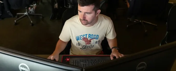 react native developer Man in casual t-shirt working on dual monitors.