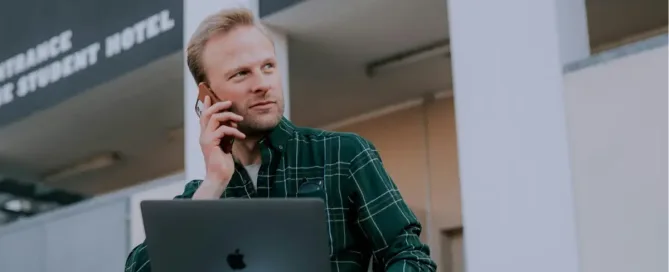 401(k) guidelines: man in green and black plaid dress shirt and blue denim jeans sitting on gray concrete