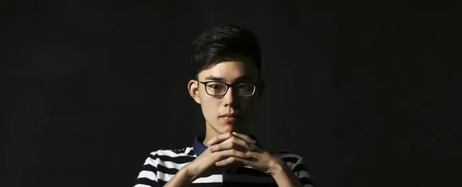 hire typescript engineers: young Asian man with glasses stares firmly at camera