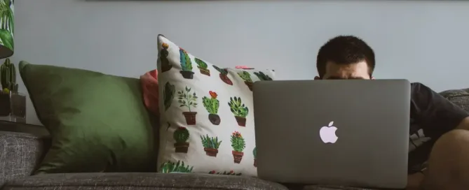 como encontrar vagas remotas: homem usando o macbook deitado no sofá