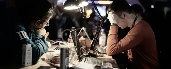 cyber security incidents: man in red long-sleeve shirt sitting in front of table with laptop computer, looking exasperated