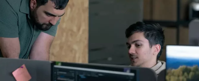 Localization Testing: Two men working on computers in an office. Code inspection with programmers