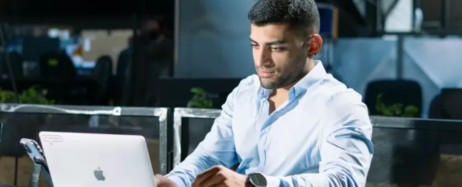 A FinOps engineer sitting at a table using a laptop computer