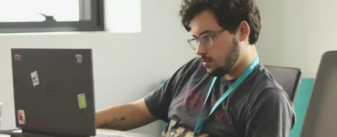 Reduce Developer Churn: A bored-looking young developer sitting in front of a laptop computer