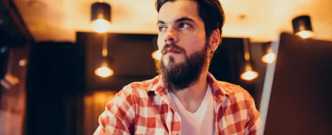 dev-for-hire: Young bearded man working on laptop in a bar