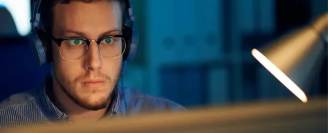 developer-ramp-up-time: Young programmer in eyewear and headphones working in office