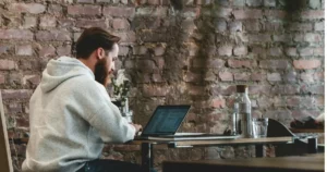 Assess Candidate Tech Skills: man in beige hoodie sitting on chair using laptop computer