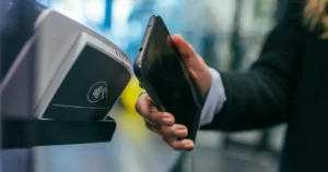 FinTech and IoT: woman holding Android smartphone to make Mobile Payment using Payment Terminal