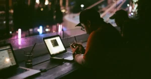 Nearshore App Development for Blockchain: person working late, facing laptop inside dark room