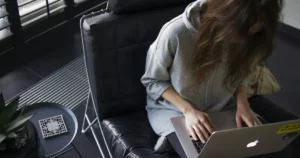 api security: woman in blue chambray long-sleeved top sitting on black leather chair with silver MacBook on lap