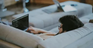 developer burnout: man lying on couch while browsing the internet