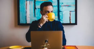 Hire a coder: man drinking coffee in front of the laptop computer