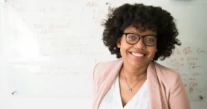 market research tools: female marketer smiles in front of whiteboard