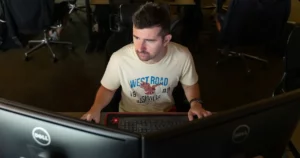 react native developer Man in casual t-shirt working on dual monitors.