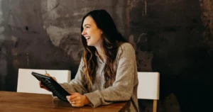 talent acquisition pipeline: smiling woman sitting around table holding tablet